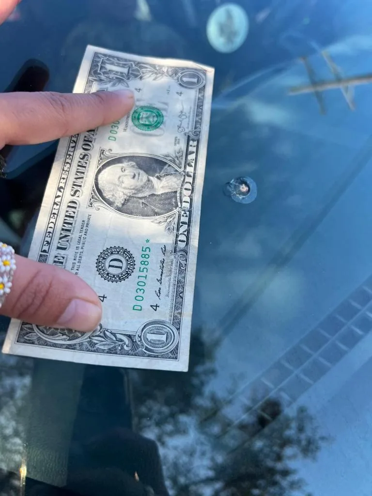 A small rock chip in a windshield, smaller than a dollar bill